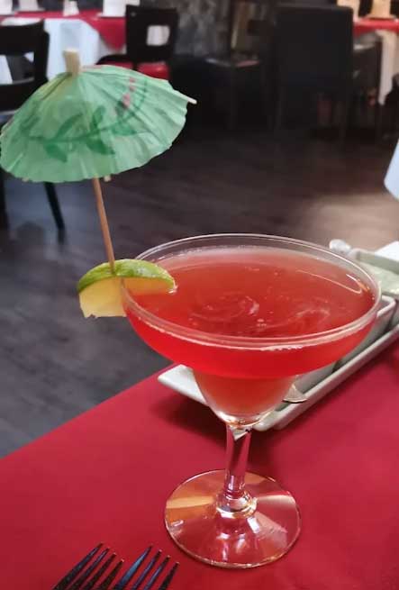 A vibrant red cocktail in a glass garnished with a lime wedge at The Dine restaurant in Broxburn. 